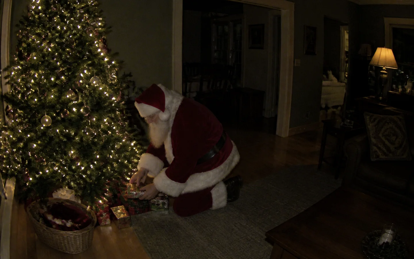 Santa Claus caught by a living room security camera beside a Christmas tree