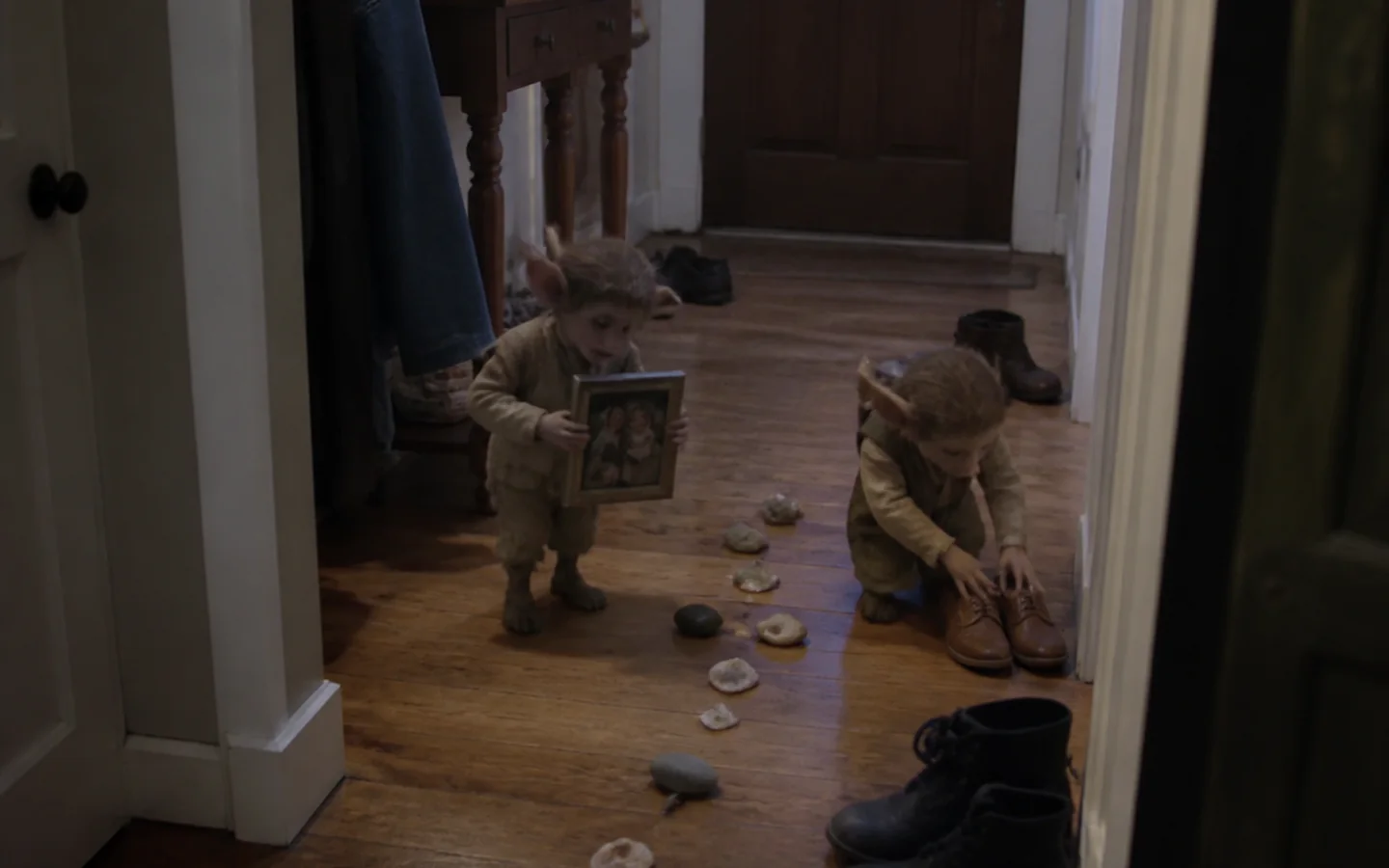 Two small household guardians caught moving family keepsakes in a hallway