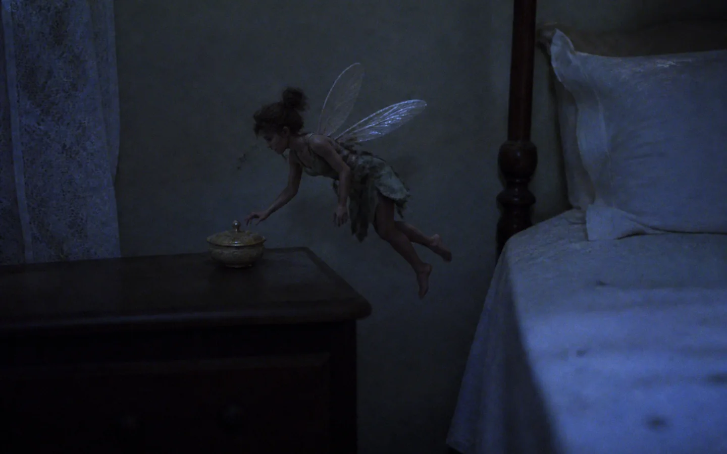 A tiny winged Tooth Fairy caught hovering beside a real bed at night